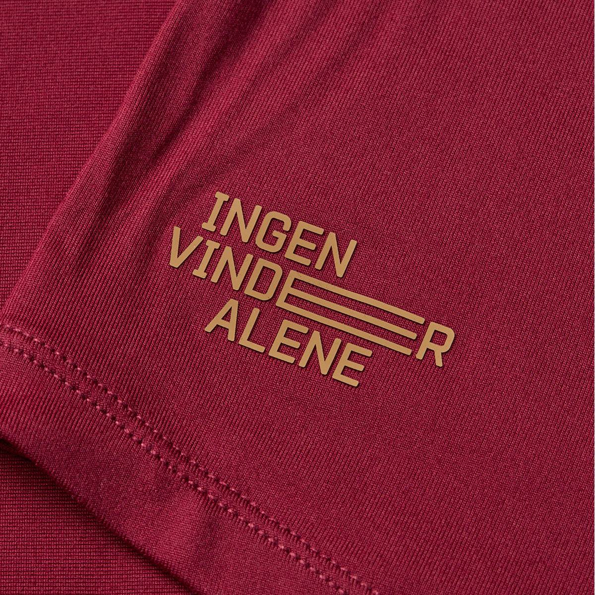 Rød T-shirt med teksten "Ingen vinder alene" på ærmet