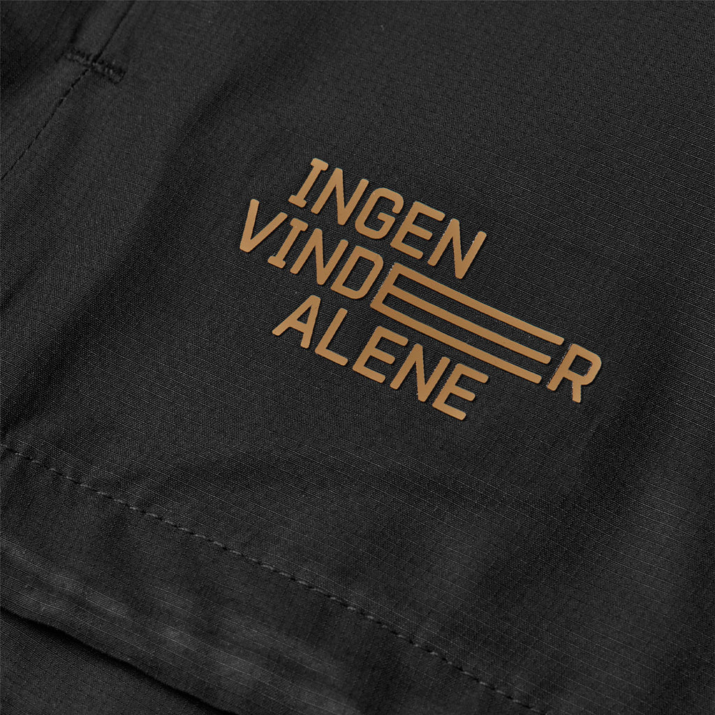 Sort windjakke med teksttryk "Ingen vinder alene